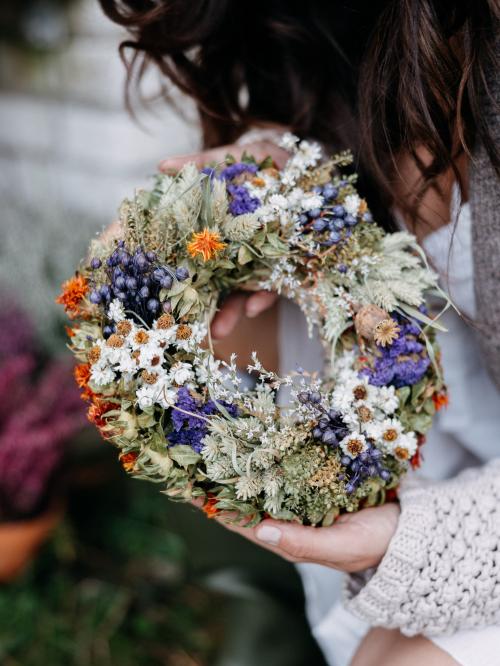 suszony wianek mały z fioletowymi kwiatami trzymany w dłoniach