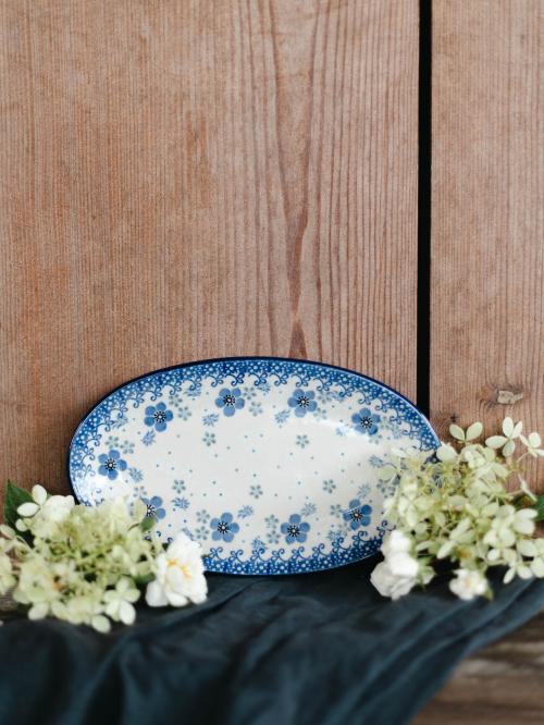 Półmisek ceramiczny na drewnianym tle wśród kwiatów