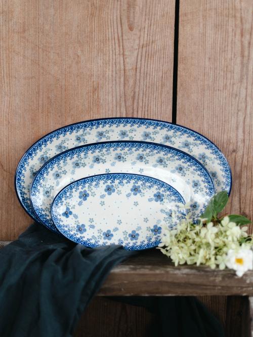 Półmiski ceramiczne na drewnianym tle wśród kwiatów