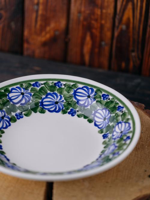 Głęboki talerz przodem na tle drewna