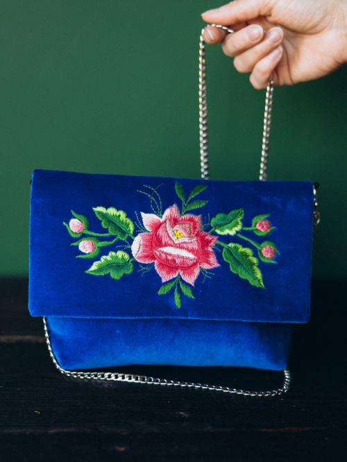 kopertówka haftowana niebieska z łańcuszkiem  trzymanym w ręku