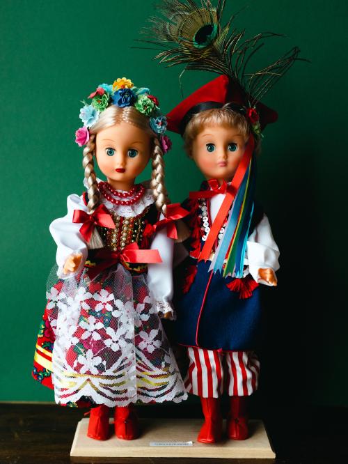 Lalki w strojach krakowskich na zielonym tle.