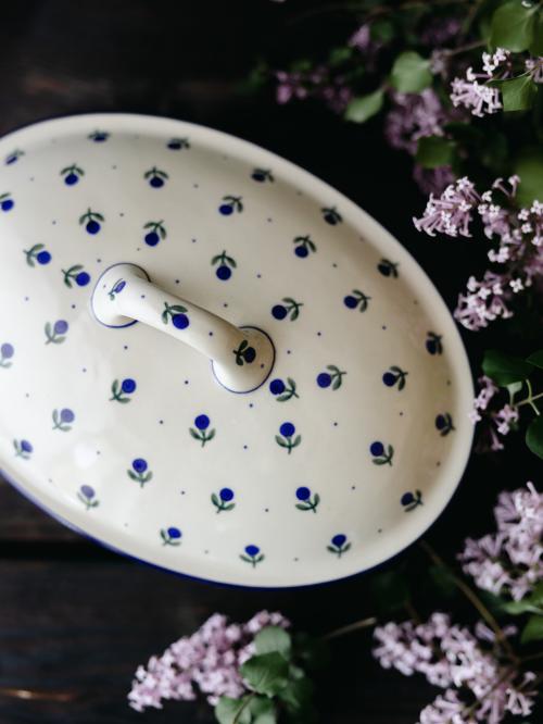 Ceramiczna zapiekanka z pokrywką uchwycona od góry na tle bzów.