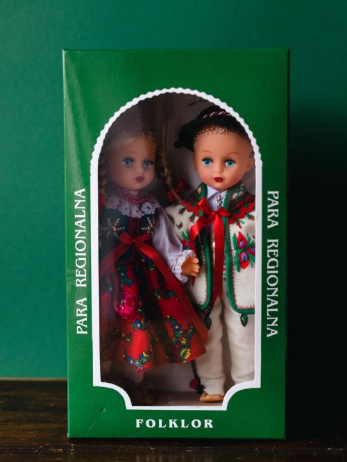 Lalki w pudełku w strojach góralskich na zielonym tle.