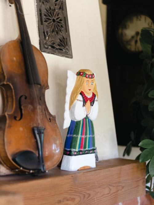 anioł rzeźbiony w łowickim pasiaku  na tle białej ściany