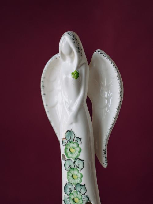 anioł średni zielony z fajansu włocławskiego na bordowym tle