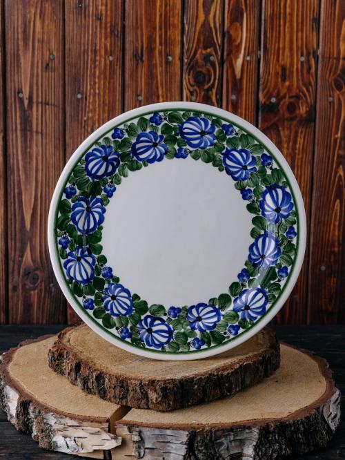 Płaski talerz z malowanym wzorem na tle drewna