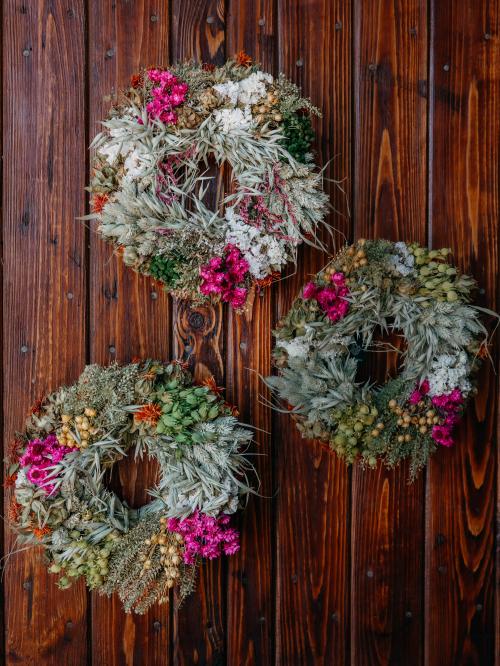trzy suszone małe wianki w kolorach różu i bieli na brązowym tyle