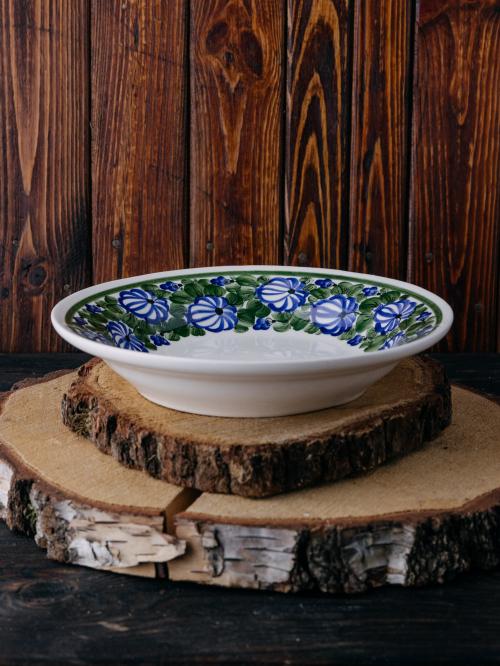 Głęboki talerz z malowanym wzorem na ciemnym tle.