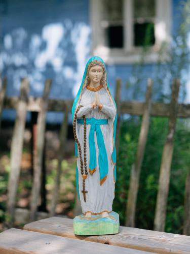 Rzeźbiona Maryja w turkusowej szacie z różańcem